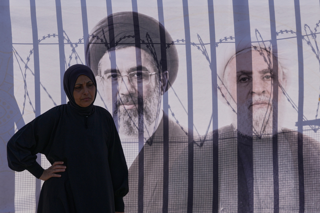 A Hezbollah supporter stands next of a banner that shows portraits of Iran's Supreme Leader Mojtaba Khamenei, left, and Hezbollah leader Sheikh Naim Qassem, as she attends the holy day of Ashoura that commemorates the 7th century martyrdom of the Prophet Muhammad's grandson Hussein, in Dahiyeh, Beirut's southern suburbs, Lebanon, Friday, June 26, 2026. (AP Photo/Hussein Malla)