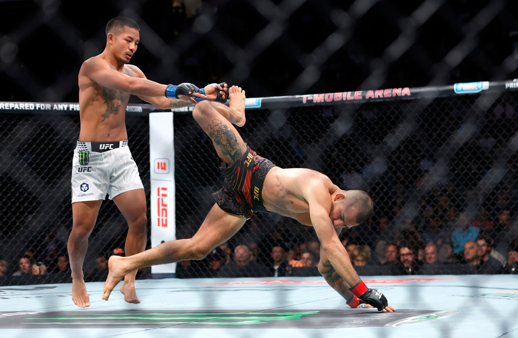 UFC flyweight champion Alexandre Pantoja, right, is injured as he falls to the canvas away from Joshua Van during UFC 323 Saturday, Dec. 6, 2025, in Las Vegas. (Steve Marcus/Las Vegas Sun via AP)