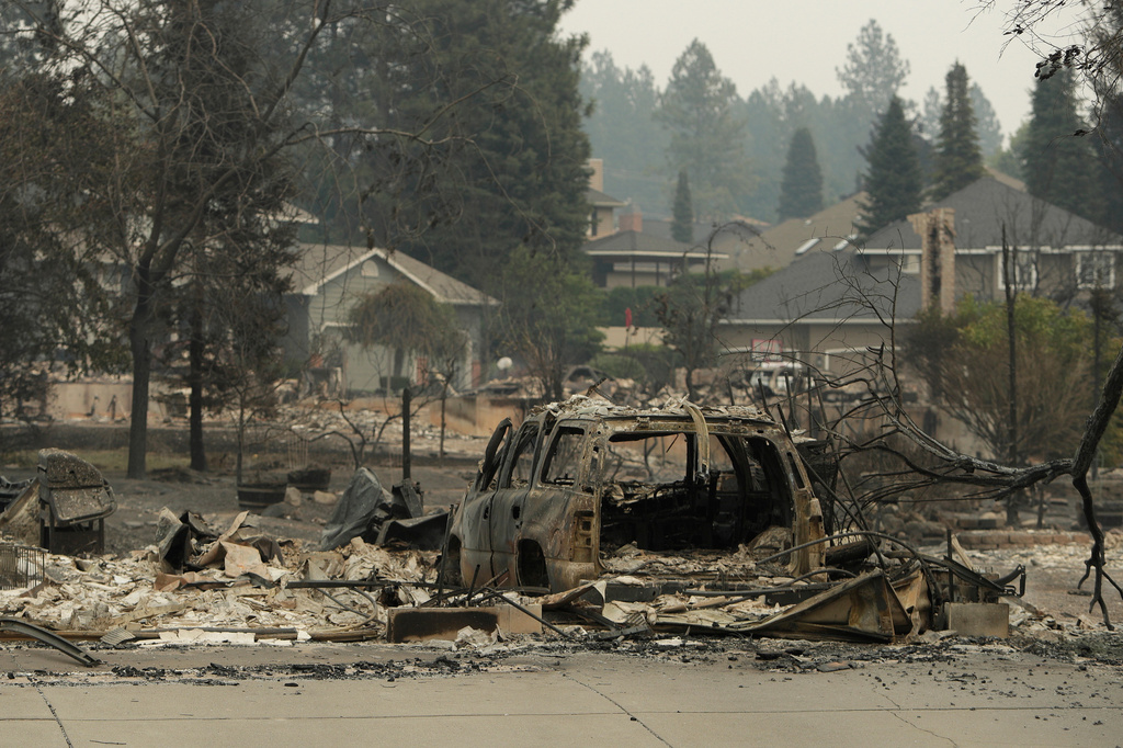 A vehicle and structure are burned on N. Skyline Dr. due to a wildfire, Sunday, Aug. 2, 2026, in Spokane, Wash. (AP Photo/Young Kwak)