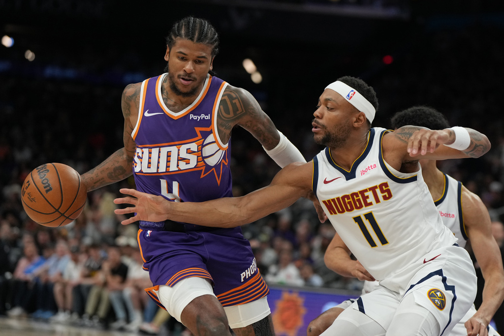 Phoenix Suns guard Jalen Green (4) shields the ball from Denver Nuggets guard/forward Bruce Brown during the first half of an NBA basketball game, Tuesday, March 24, 2026, in Phoenix. (AP Photo/Rick Scuteri)