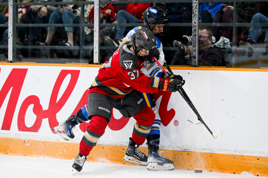 Ottawa Charge's Rebecca Leslie (37) pins Toronto Sceptres' Kali Flanagan (6) against the boards while battling for the puck during the first period of a PWHL hockey game in Ottawa, Ontario, Saturday, April 25, 2026. (Spencer Colby/The Canadian Press via AP)