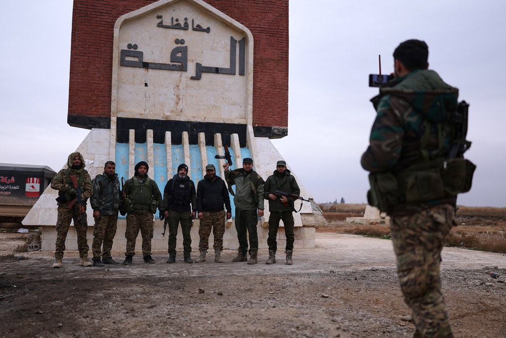 Syrian government soldiers pose for a photo taken by another soldier at the entrance to Raqqa, Syria, Saturday, Jan. 17, 2026. (AP Photo/Ghaith Alsayed)