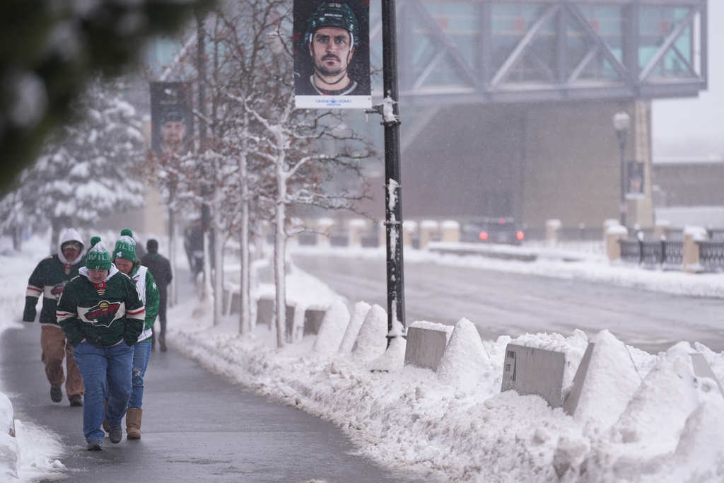 Fans walk through snowy streets before an NHL hockey game between the Minnesota Wild and Toronto Maple Leafs, Sunday, March 15, 2026, in St. Paul. (AP Photo/Abbie Parr)