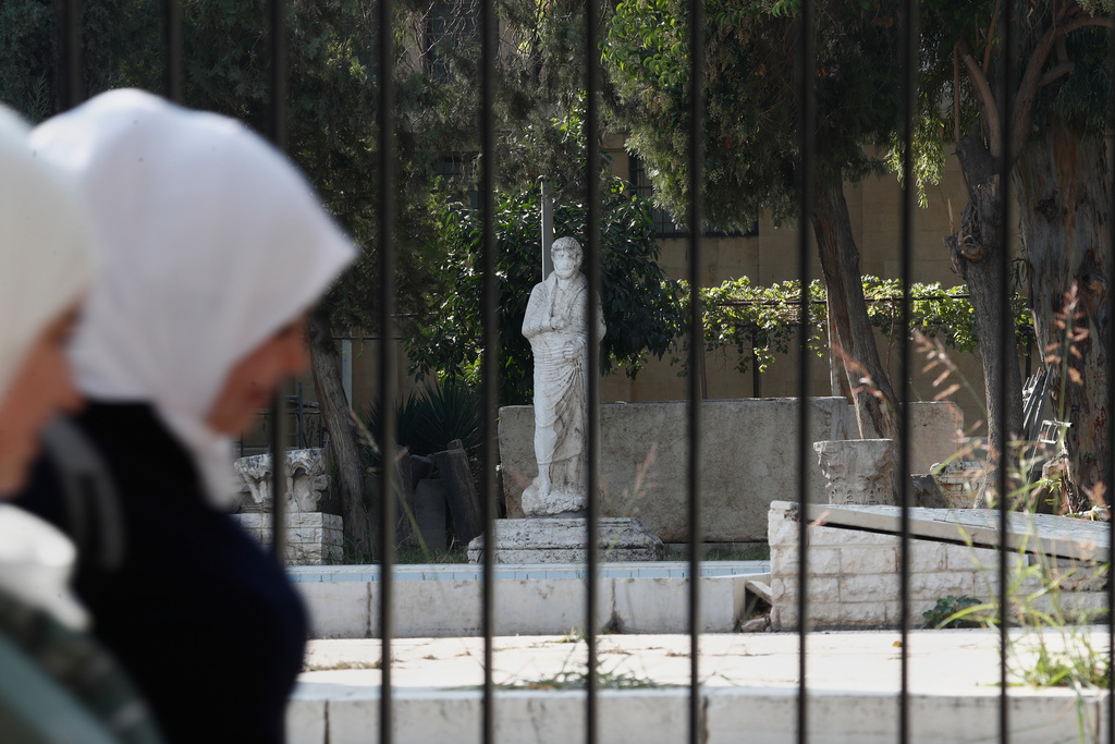 Syrian women walk past a fence of the National Museum of Syria in Damascus, Syria, Wednesday, Nov. 12, 2025. (AP Photo/Omar Sanadiki)
