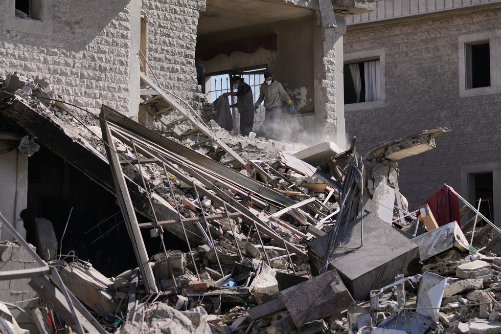 People collect the remains of their belongings from a building destroyed in an Israeli strike in the village of Bednayel in eastern Lebanon, Saturday, Feb. 21, 2026. (AP Photo/Bilal Hussein)