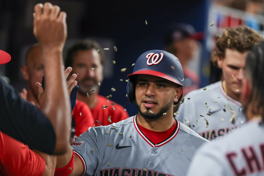 Washington Nationals teammates congratulate Keibert Ruiz, center, after Ruiz hit a solo home run during the sixth inning of a baseball game against the Miami Marlins, Friday, Aug. 21, 2026, in Miami. (AP Photo/David Santiago)