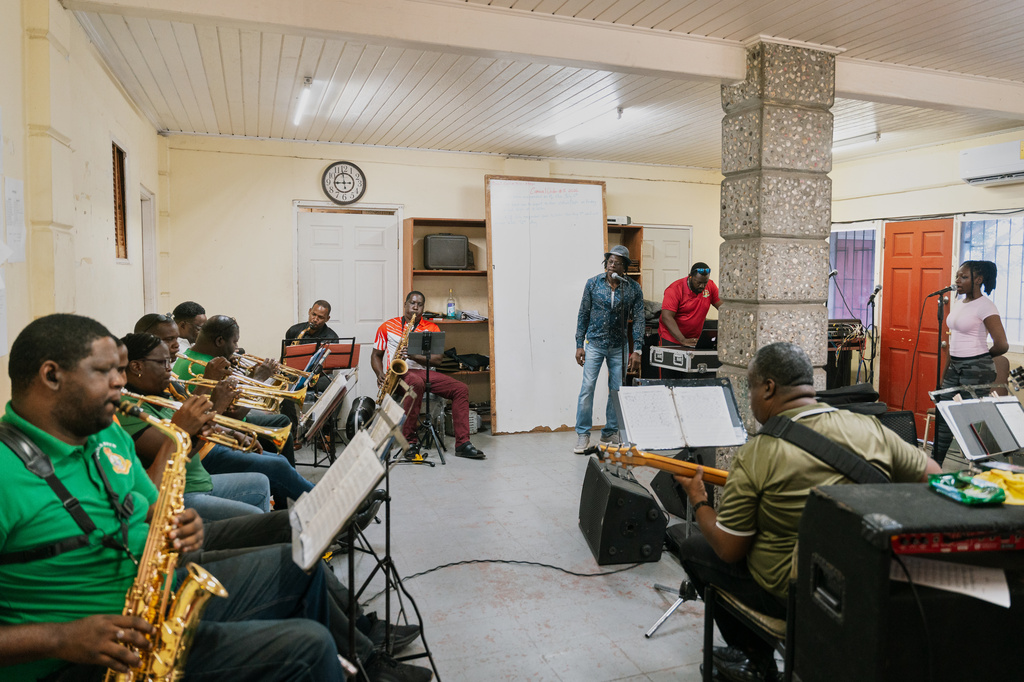 Father Gerard Paul, back center, who can no longer officiate masses, funerals, weddings or baptisms after repeatedly criticizing the church and clergy, rehearses with Royal Grenada Police Force Band in St. George, Grenada, Thursday, Aug. 6, 2026. (AP Photo/Floyd Robinson)