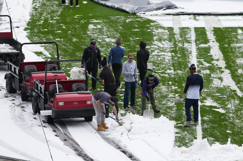 Grounds crew members toil to clear snow from the outfield of Coors Field after a spring storm blanketed the intermountain West before the Colorado Rockies host the Los Angeles Dodgers in a baseball game Friday, April 17, 2026, in Denver. (AP Photo/David Zalubowski)