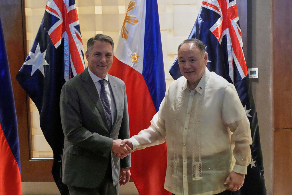 Philippine Defense Secretary Gilberto Teodoro, right, shakes hands with his Australian counterpart Richard Marles prior to their meeting at a hotel in Makati, Philippines, on Friday, Aug. 22, 2025. (AP Photo/Aaron Favila)