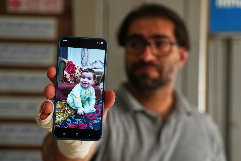 Fahd Abu Haikal, 41 displays a mobile photo of his seven month old Palestinian baby boy Sam, who was killed on Friday when Israeli soldiers fired at the vehicle carrying him and his parents, in Tel Rumeida, at a hospital in the West Bank city of Hebron Saturday, June 6, 2026. (AP Photo/Mahmoud Illean)