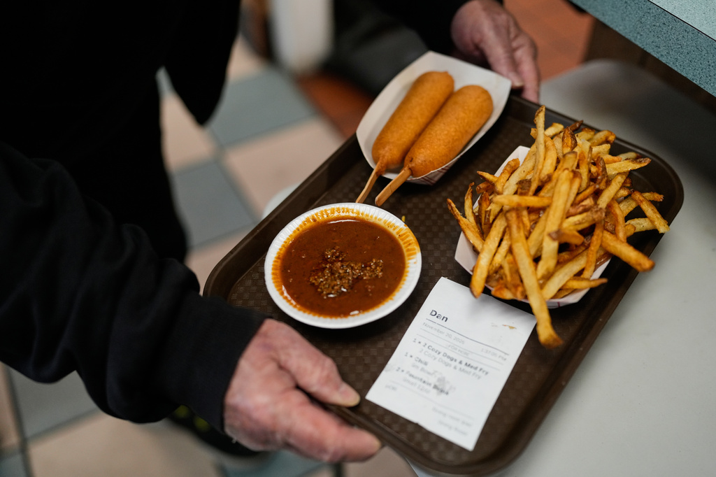 A customer picks up their order at the Cozy Dog Drive In, in Springfield, Ill., Thursday, Nov. 20, 2025. (AP Photo/Jeff Roberson)