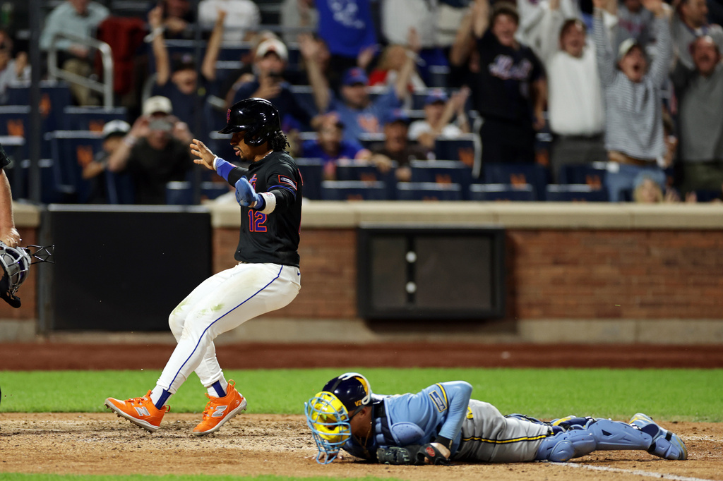 New York Mets' Francisco Lindor scores the winning run past Milwaukee Brewers catcher William Contreras during the 10th inning of a baseball game on Tuesday, Aug. 25, 2026, in New York. (AP Photo/Adam Hunger)