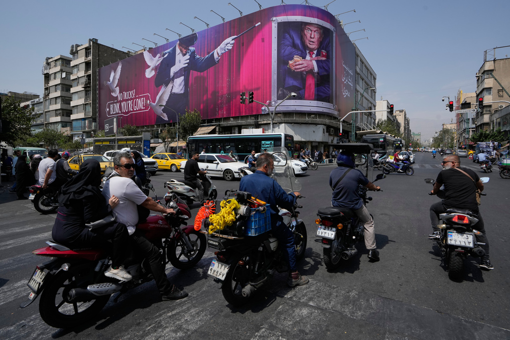 Vehicles pass a billboard depicting U.S. President Donald Trump inside a catering container alongside a magician and the words "No tricks! Blink, you're gone," in downtown Tehran, Iran, Monday, Aug. 31, 2026. (AP Photo/Vahid Salemi)