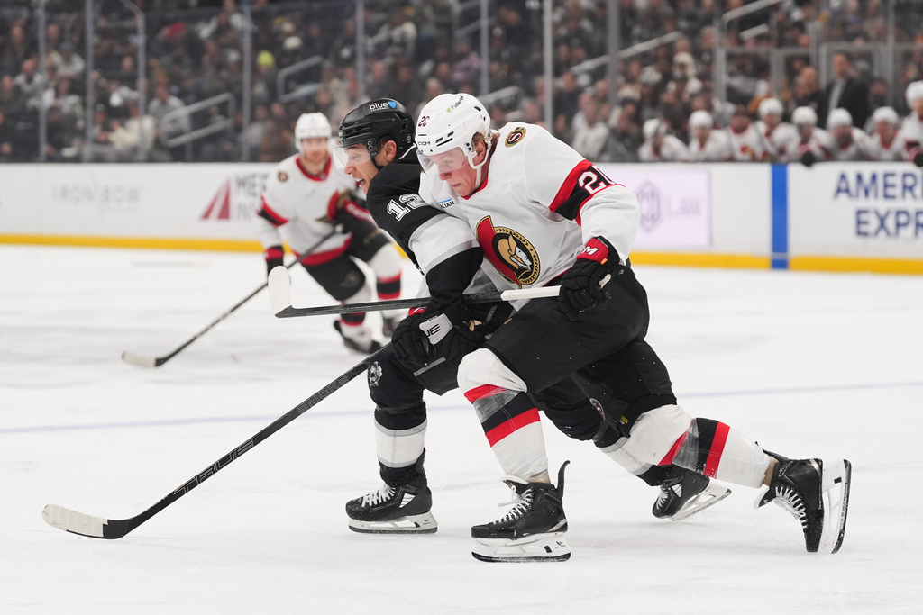 Los Angeles Kings left wing Trevor Moore (12) and Ottawa Senators left wing Fabian Zetterlund (20) chase the puck during the third period of an NHL hockey game Monday, Nov. 24, 2025, in Los Angeles. (AP Photo/Jae C. Hong)