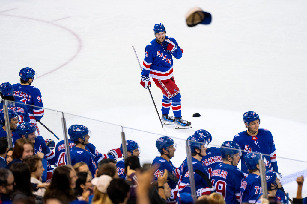 Fans celebrate as New York Rangers left wing Alexis Lafrenière (13) makes a hat trick after scoring his third goal, the team's fourth, against the Calgary Flames during the third period of an NHL hockey game, Tuesday, March 10, 2026, in New York. (AP Photo/Angelina Katsanis)
