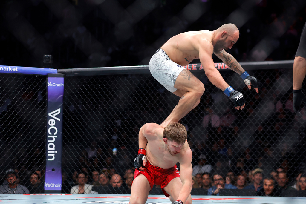 Jean Silva, top, jumps on the back of Arnold Allen, bottom, in a featherweight bout during the UFC 324 mixed martial arts event Saturday, Jan. 24, 2026, in Las Vegas. (AP Photo/Steve Marcus)