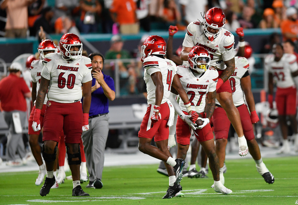 Louisville defensive back Jojo Evans Jr. (27) celebrates after intercepting a pass with defensive lineman Jordan Guerad (99) during the second half of an NCAA college football game against Miami, Friday, Oct. 17, 2025, in Miami Gardens, Fla. (AP Photo/Michael Laughlin)