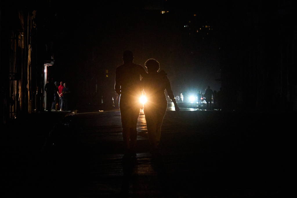 People cross a street during a blackout in Havana, Wednesday, March 4, 2026. (AP Photo/Ramon Espinosa)