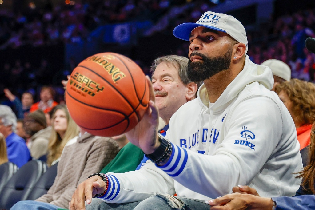Former NBA player Carlos Boozer, father of Duke forward Cameron Boozer and guard Cayden Boozer, tosses the ball back to an official as he watches Duke play against Clemson during the first half of an NCAA college basketball game in the semifinals of the Atlantic Coast Conference tournament in Charlotte, N.C., Friday, March 13, 2026. (AP Photo/Nell Redmond)