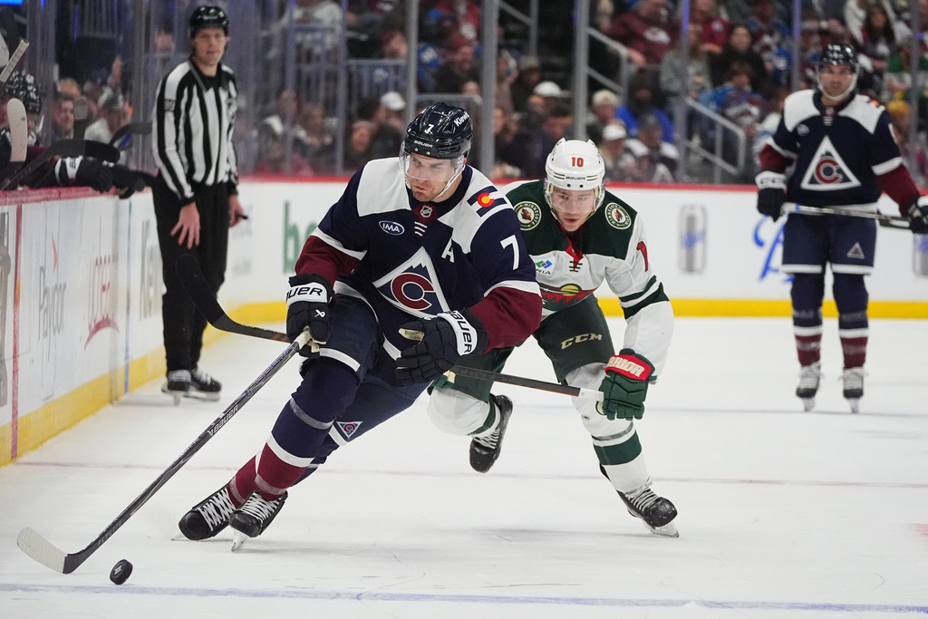 Colorado Avalanche defenseman Devon Toews, front, collects the puck as Minnesota Wild right wing Bobby Brink pursues in the second period of an NHL hockey game, Sunday, March 8, 2026, in Denver. (AP Photo/David Zalubowski)