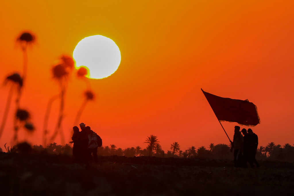 The sun rises as Shiite pilgrims march on their way, to Karbala, to observe Arbaeen that marks the end of a 40-day mourning period following the Day of Ashura, in Najaf, Iraq, Tuesday, July 28, 2026. (AP Photo/Anmar Khalil)