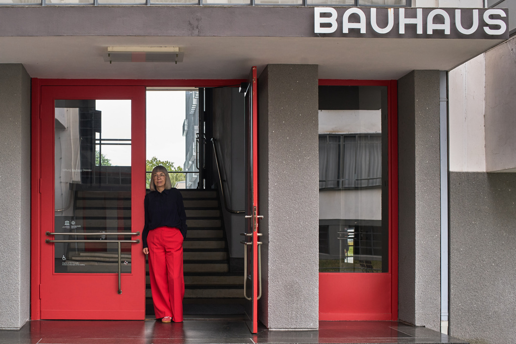 Barbara Steiner, the director of the Bauhaus Dessau Foundation poses for a photo at the entrance of the main building of the former design school, which was called an "aberration of modernism" by Germany's far-right Alternative for Germany party, in Dessau, Germany, Aug. 17, 2026. (AP Photo/Markus Schreiber)