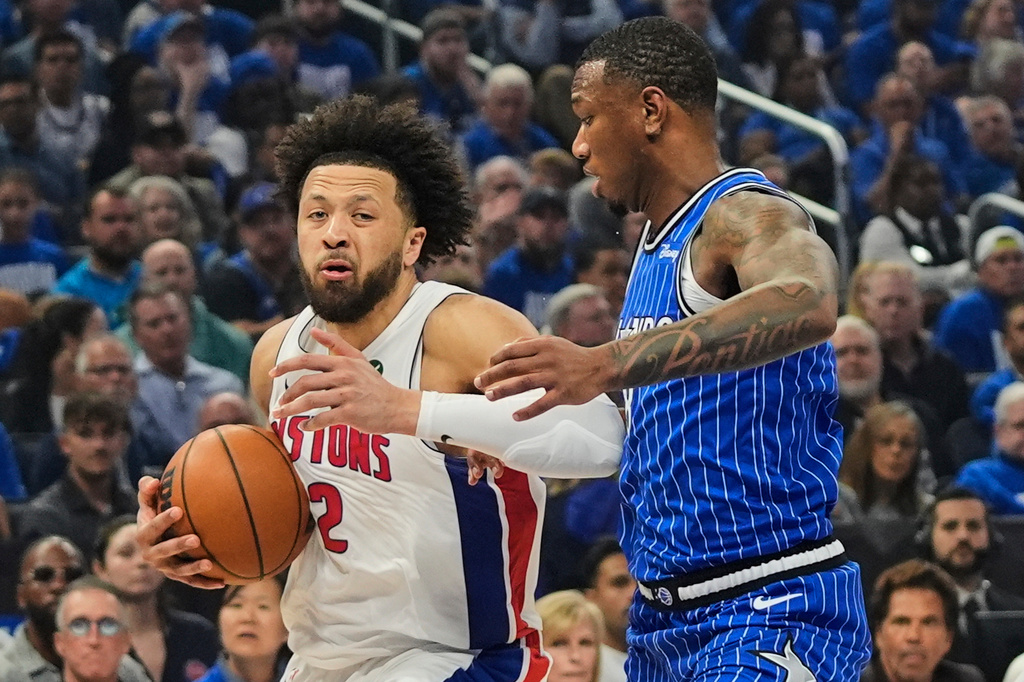 Detroit Pistons guard Cade Cunningham, left, moves past Orlando Magic forward Jamal Cain during the first half in Game 4 of a first-round NBA basketball playoff series, Monday, April 27, 2026, in Orlando, Fla. (AP Photo/John Raoux)