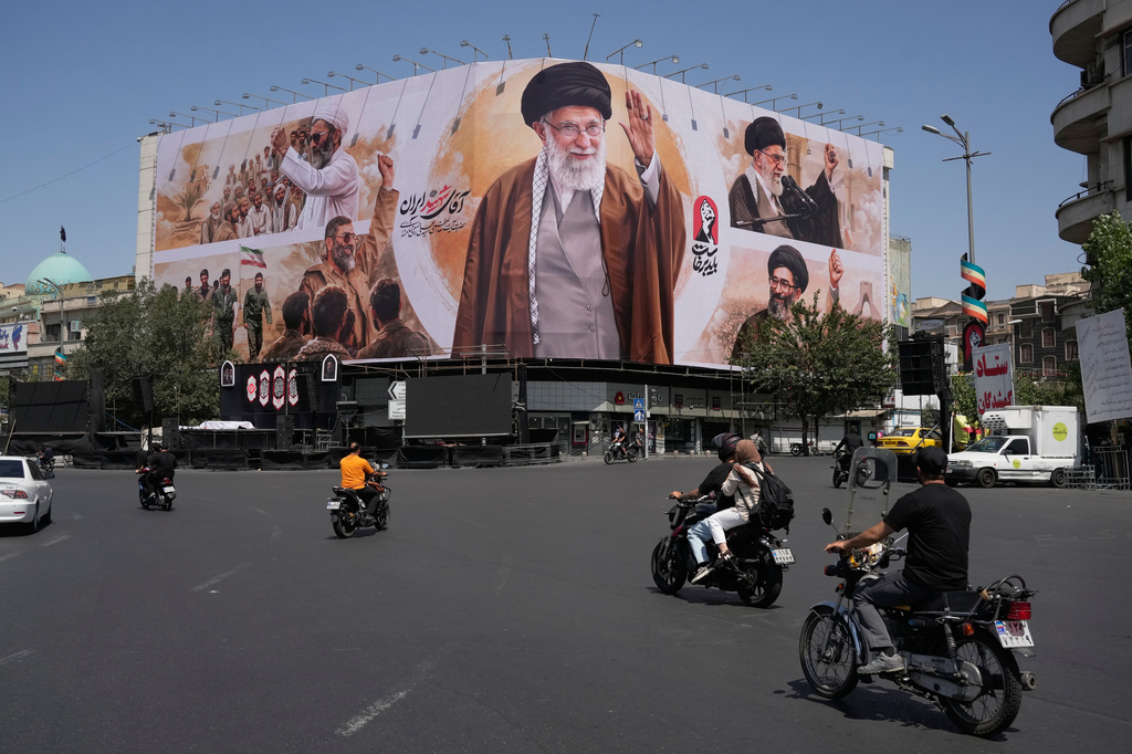 Motorcycles drive past a billboard showing the late Iranian Supreme Leader Ayatollah Ali Khamenei in Islamic Revolution Square in Tehran, Iran, Sunday, July 5, 2026. (AP Photo/Vahid Salemi)