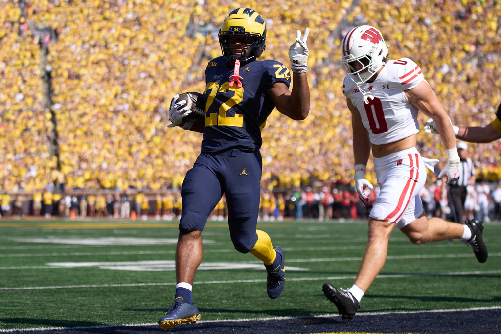 Michigan running back Justice Hayne, left, gestures ahead of Wisconsin linebacker Christian Alliegro after scoring a touchdown during the first half of an NCAA college football game, Saturday, Oct. 4, 2025, in Ann Arbor, Mich. (AP Photo/Ryan Sun)
