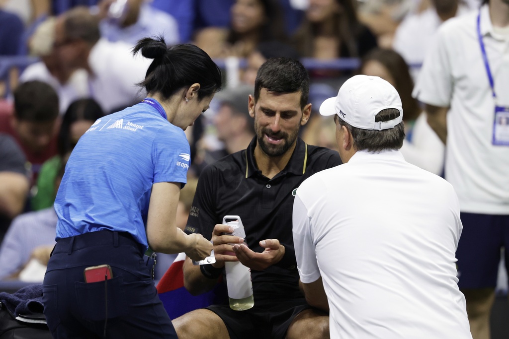 Novak Djokovic, of Serbia, talks with trainers during the third round match against Cameron Norrie, of Great Britain, of the U.S . Open tennis championships, Friday, Aug. 29, 2025, in New York. (AP Photo/Adam Hunger)