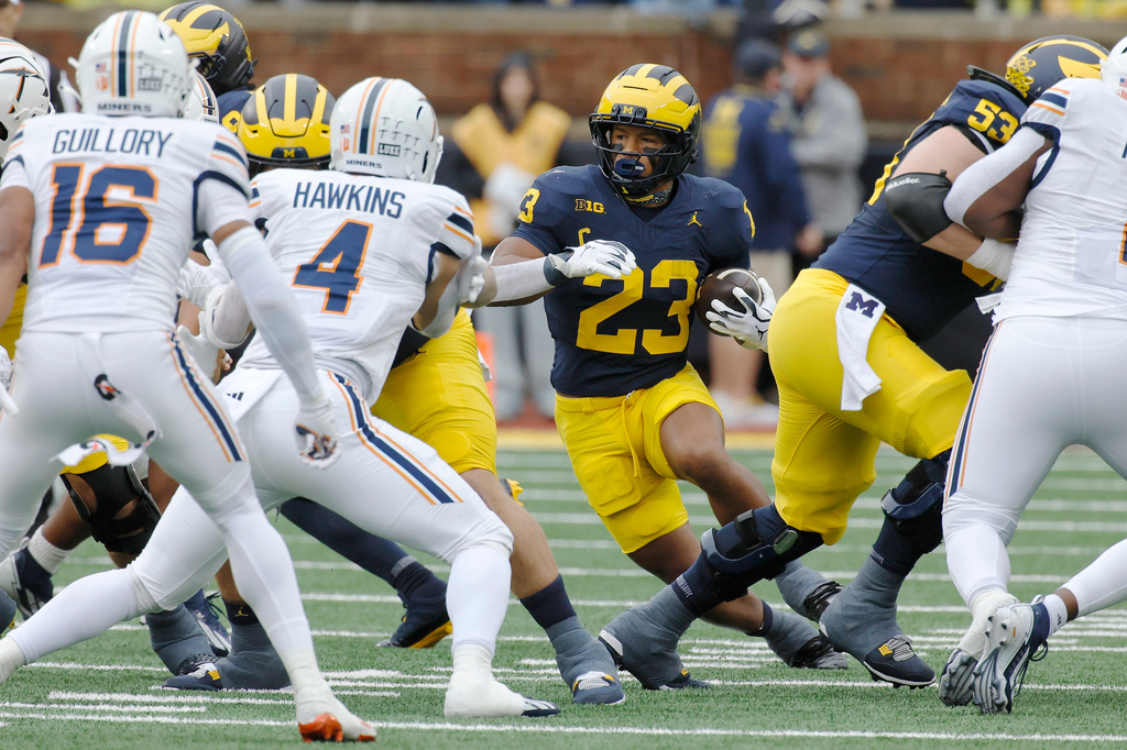 Michigan running back Jordan Marshall (23) carries the ball against UTEP safety Esteban Guillory (16) and linebacker Garrett Hawkins (4) during the first half of an NCAA college football game Saturday, Sept. 19, 2026, in Ann Arbor, Mich. (AP Photo/Duane Burleson)
