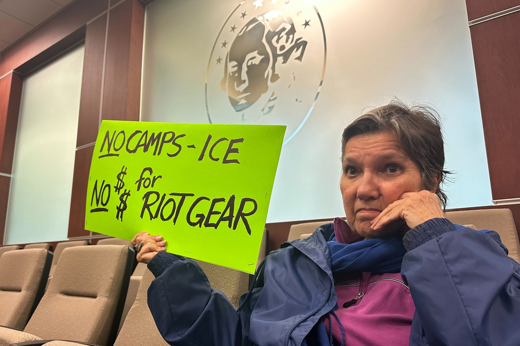 Carol Antoniewicz holds a sign against a planned immigration detention facility during a a Washington County Commission meeting in Hagerstown, Md., Tuesday, March 31, 2026. (AP Photo/Nathan Ellgren)