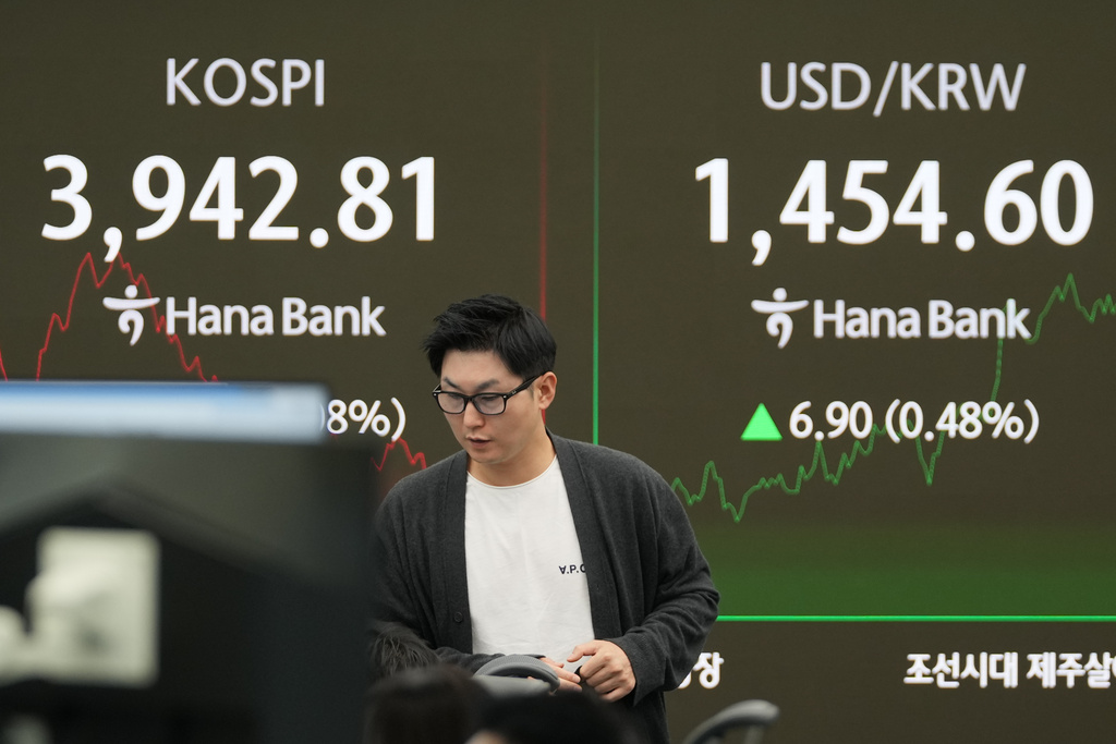 A dealer walks past near the screens showing the Korea Composite Stock Price Index (KOSPI), left, and the foreign exchange rate between U.S. dollar and South Korean won at a dealing room of Hana Bank in Seoul, South Korea, Friday, Nov. 7, 2025. (AP Photo/Lee Jin-man)