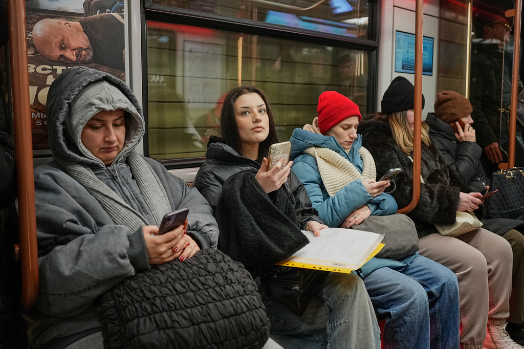 FILE - Passengers look at their smartphones in the subway in Moscow, Feb. 11, 2026. (AP Photo/Alexander Zemlianichenko, File)