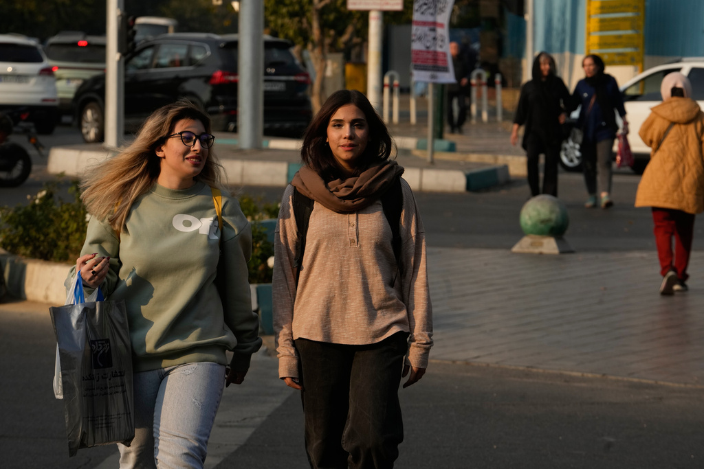 Women cross an intersection in downtown Tehran, Iran, Thursday, Nov. 20, 2025. (AP Photo/Vahid Salemi)