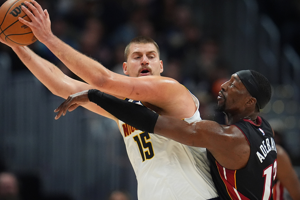 Denver Nuggets center Nikola Jokic, left, looks to pass the ball as Miami Heat center Bam Adebayo defends in the first half of an NBA basketball game Wednesday, Nov. 5, 2025, in Denver. (AP Photo/David Zalubowski)