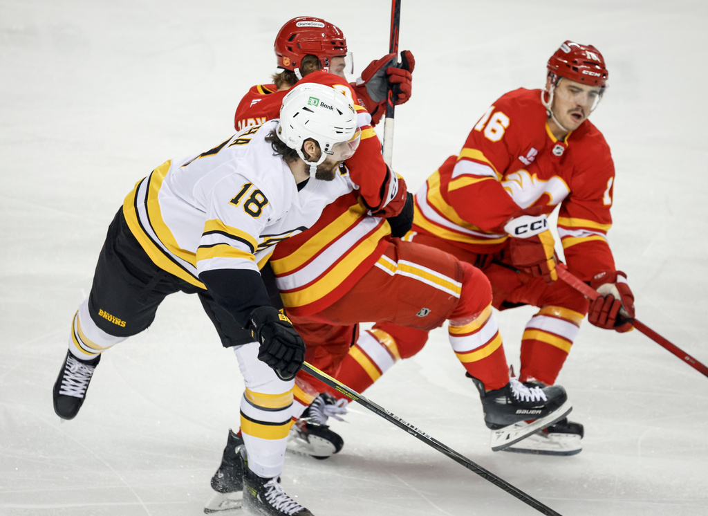 Boston Bruins' Pavel Zacha, left, checks Calgary Flames' Connor Zary, centre, as Morgan Frost chases the puck during the first period of an NHL hockey game, in Calgary, Alberta, Monday, Dec. 29, 2025. (Jeff McIntosh/The Canadian Press via AP)