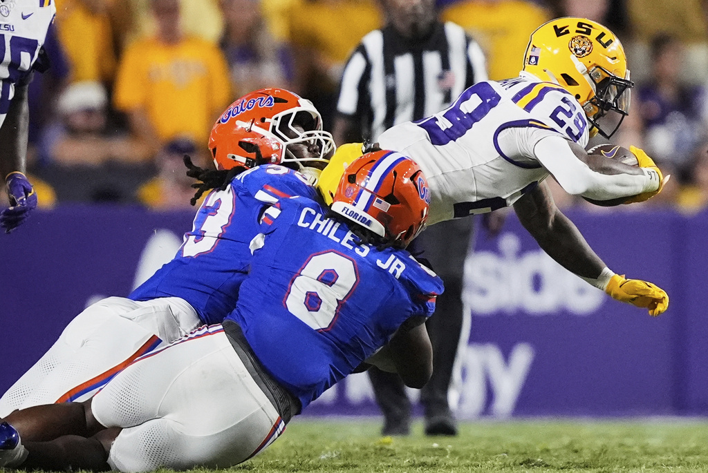 LSU running back Caden Durham (29) is tackled by Florida linebacker Aaron Chiles (8) and defensive lineman Brien Taylor Jr. in the second half of an NCAA college football game, Saturday, Sept. 13, 2025, in Baton Rouge, La. (AP Photo/Gerald Herbert)