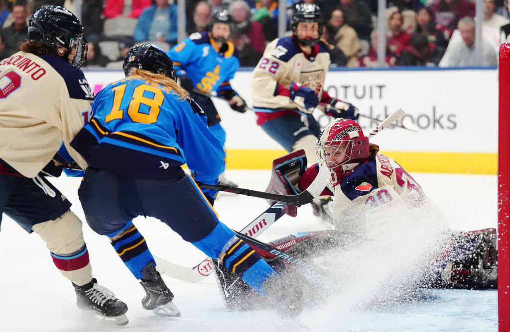 Montreal Victoire goaltender Sandra Abstreiter (30) makes a save on Toronto Sceptres' Jesse Compher (18) as Tamara Giaquinto (12) defends during the second period of an PWHL hockey game in Toronto, Tuesday, March 3, 2026. (Frank Gunn/The Canadian Press via AP)