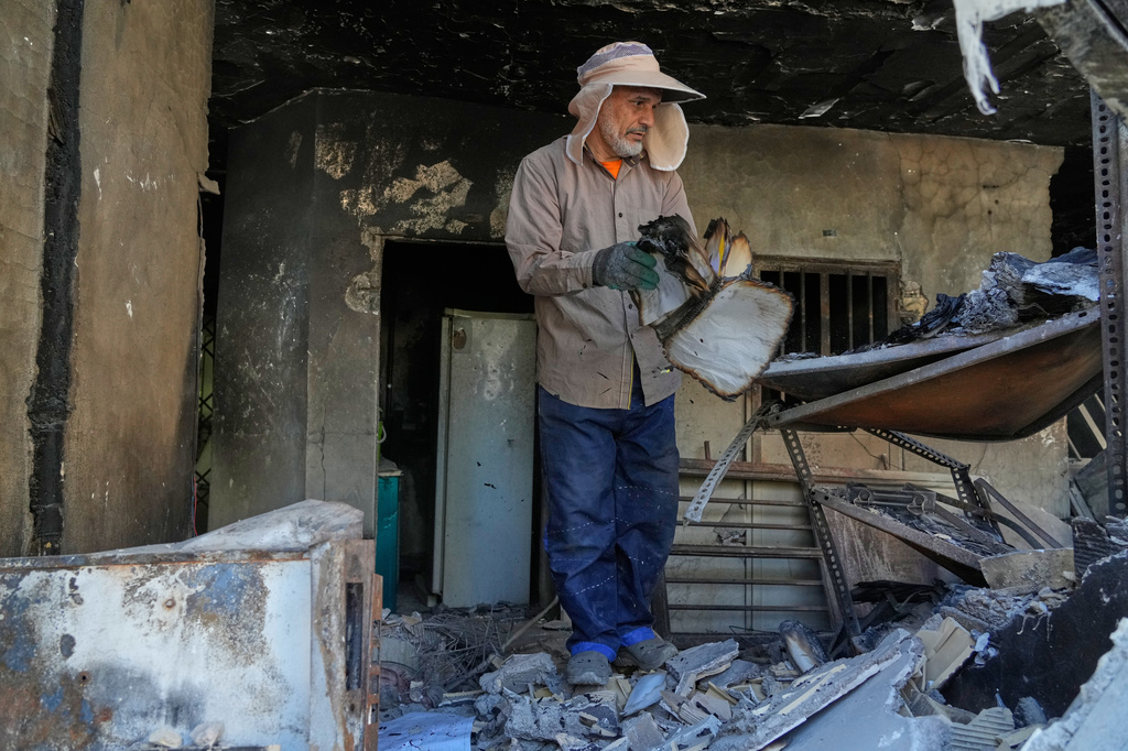 A volunteer flips a burnt book amid the debris of a residential building that, according to the authorities, was damaged on March 4 during the U.S.-Israeli military campaign, in southeastern Tehran, Iran, Tuesday, April 14, 2026. (AP Photo/Vahid Salemi)