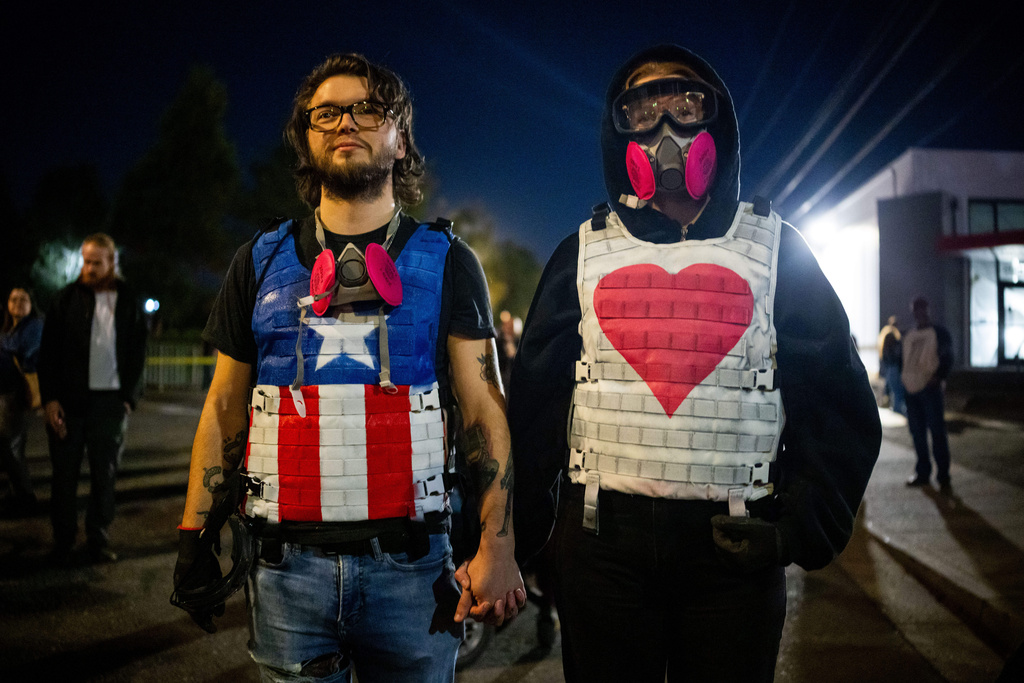Demonstrators stand outside a U.S. Immigration and Customs Enforcement facility on Tuesday, Oct. 7, 2025, in Portland, Ore. (AP Photo/Ethan Swope)
