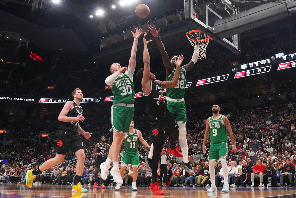 Toronto Raptors forward Scottie Barnes, center, shoots over Boston Celtics Sam Hauser (30) and Neemias Queta (88) during first-half NBA basketball game action in Toronto, Sunday Dec. 7, 2025. (Chris Young/The Canadian Press via AP)