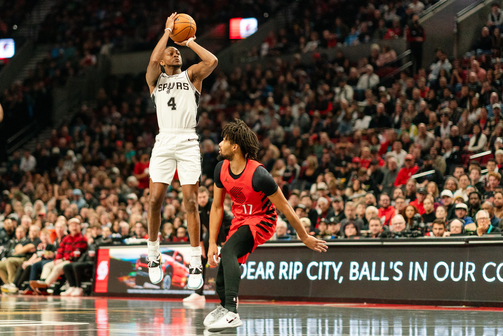 San Antonio Spurs guard De'Aaron Fox (4) shoots a three point shot over Portland Trail Blazers guard Shaedon Sharpe (17) during the first half of an Emirates NBA Cup basketball game, Wednesday, Nov. 26, 2025, in Portland, Ore. (AP Photo/Ali Gradischer)
