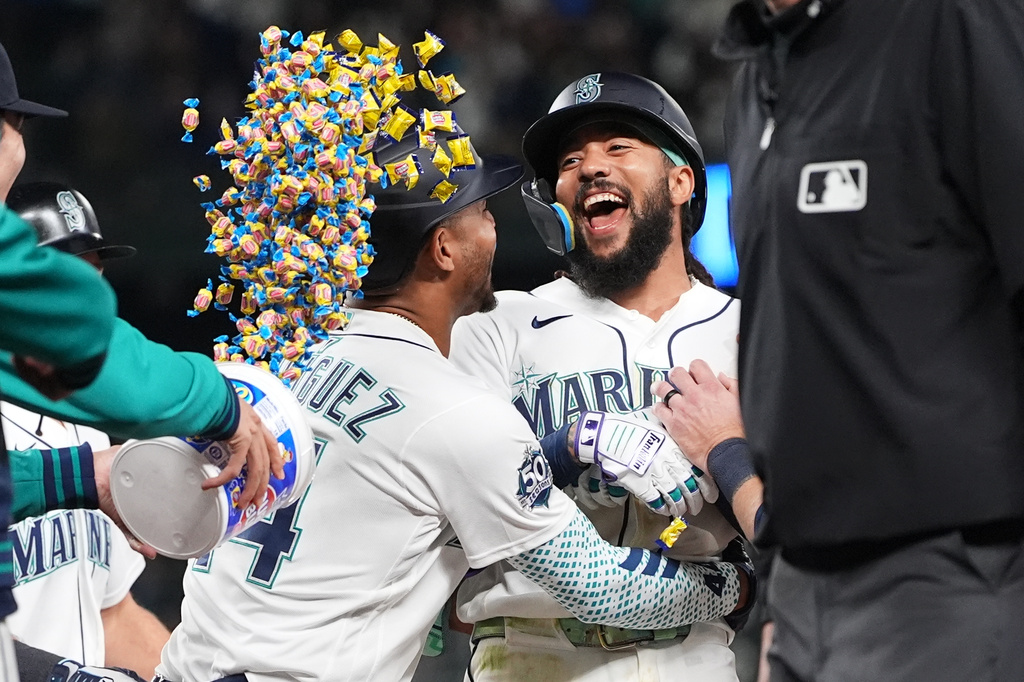 Seattle Mariners' J.P. Crawford, center, celebrates with Julio Rodríguez, left, after hitting a game-winning single to score Cole Young against the Houston Astros during the ninth inning of a baseball game, Saturday, April 11, 2026, in Seattle. (AP Photo/Lindsey Wasson)
