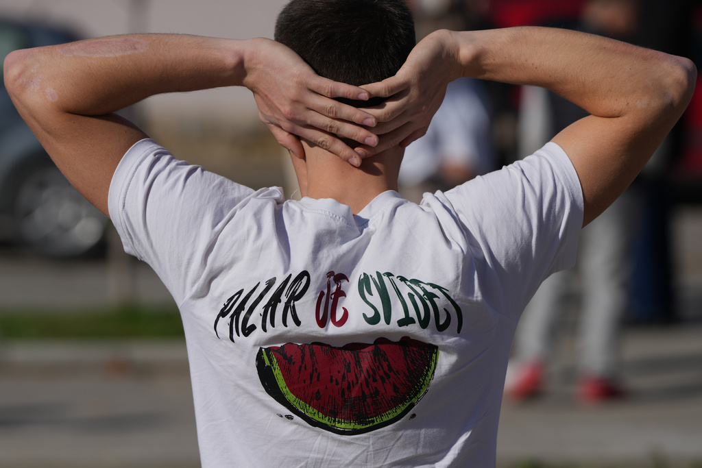 A student wearing a t-shirt reading: "Pazar is the World" rests during a march towards the northern city of Novi Sad, for a rally on Nov. 1 marking the first anniversary of a train station disaster that killed 16 people, in Ub, Serbia, Monday, Oct. 27, 2025. (AP Photo/Darko Vojinovic)