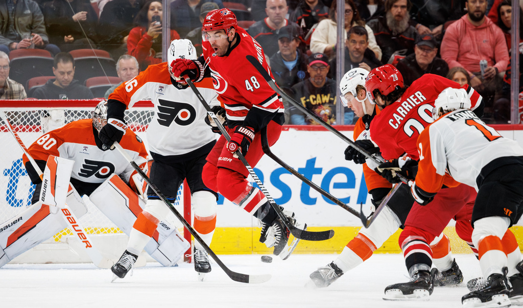 Carolina Hurricanes' Jordan Martinook (48) jumps over a shot by teammate William Carrier (28) for a goal during the first period of an NHL hockey game against the Philadelphia Flyers in Raleigh, N.C., Sunday, Dec. 14, 2025. (AP Photo/Ben McKeown)