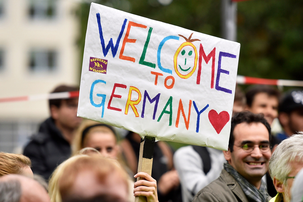 FILE - People welcome refugees with a banner reading "Welcome to Germany" in Dortmund, Germany, Sept. 6, 2015, where thousands of migrants and refugees arrived by trains. (AP Photo/Martin Meissner, File)