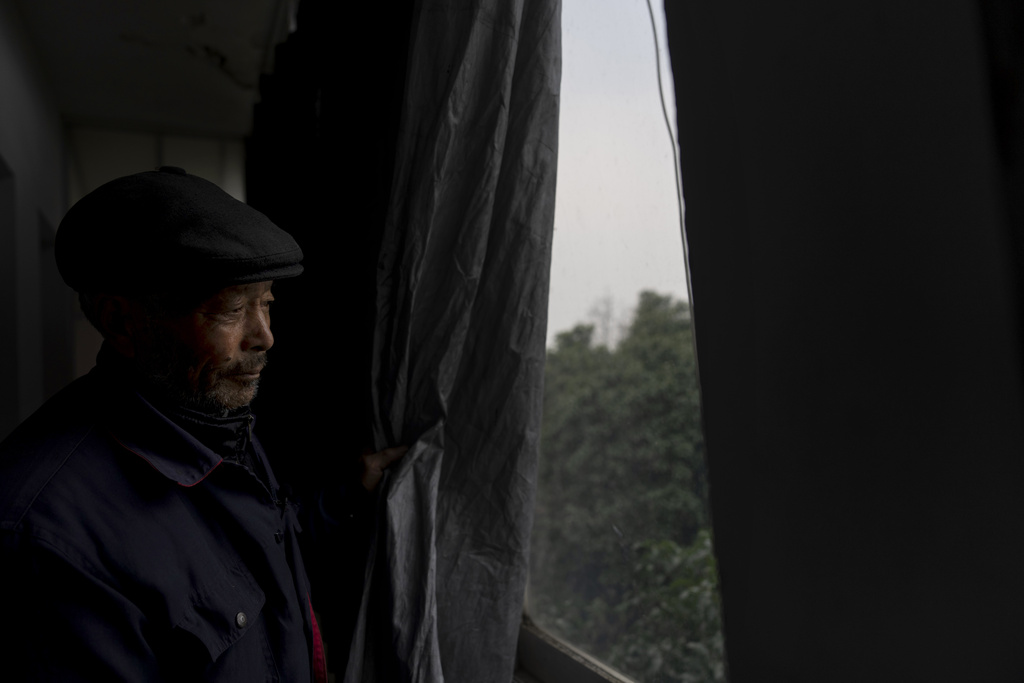 Petitioner Yang Guoliang pulls back the blackout curtain used to provide privacy from nearby police security cameras and lights during an interview at his home in Changzhou in eastern China's Jiangsu Province, Friday, Dec. 13, 2024. (AP Photo/Ng Han Guan)