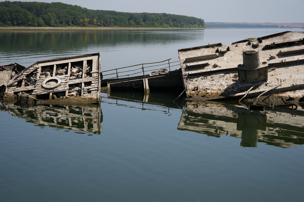 The wreckage of a WWII German warship emerges, due to the drought, in front of Djerdap II, a large dam on the Danube River, between Romania and Serbia, near Prahovo, Serbia, Tuesday, Aug. 4, 2026. (AP Photo/Darko Vojinovic)
