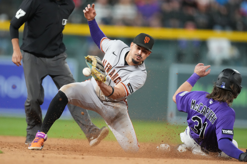 San Francisco Giants shortstop Willy Adames, front left, fields a throw as Colorado Rockies' Jake McCarthy, right, steals second base in the seventh inning of a baseball game Saturday, May 30, 2026, in Denver. (AP Photo/David Zalubowski)